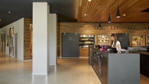 Un área de bar moderna con mostrador, estantes de bebidas e iluminación colgante.