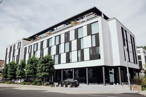 Un bâtiment moderne avec de grandes fenêtres et une voiture noire garée devant.