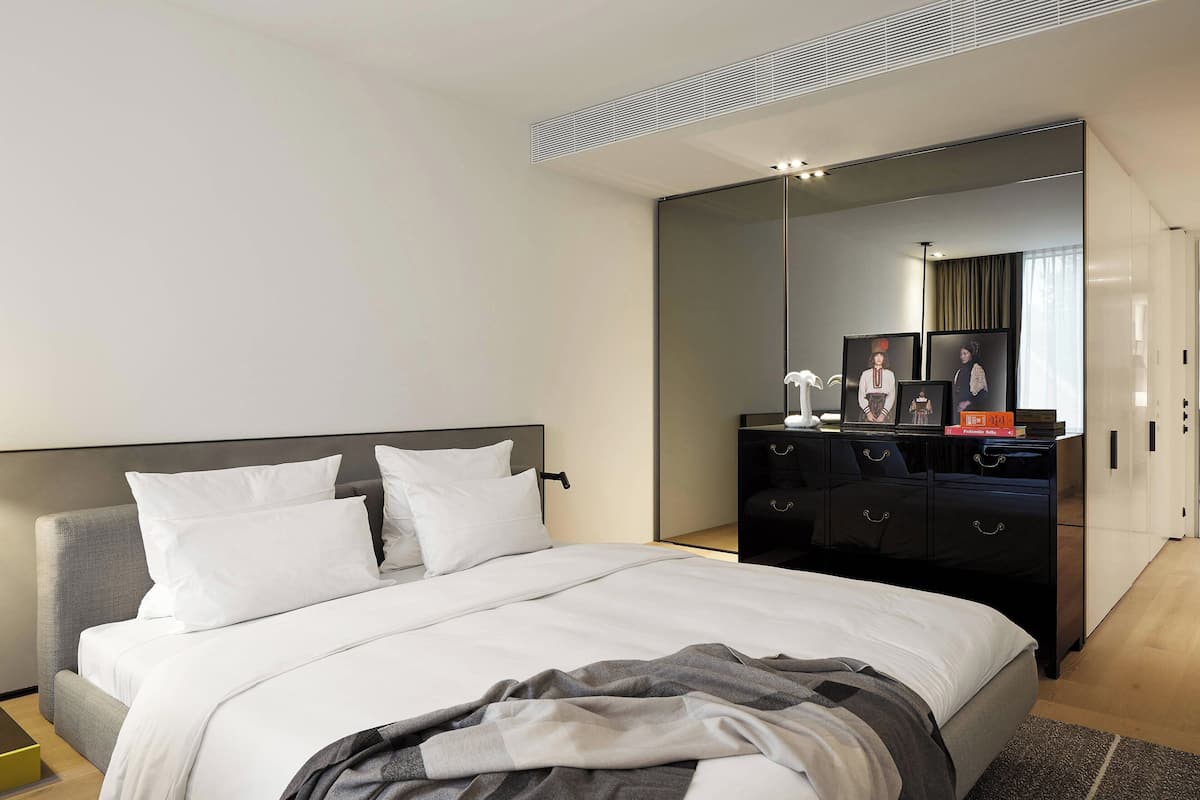 Une chambre à coucher moderne avec un grand lit, une commode et un miroir.