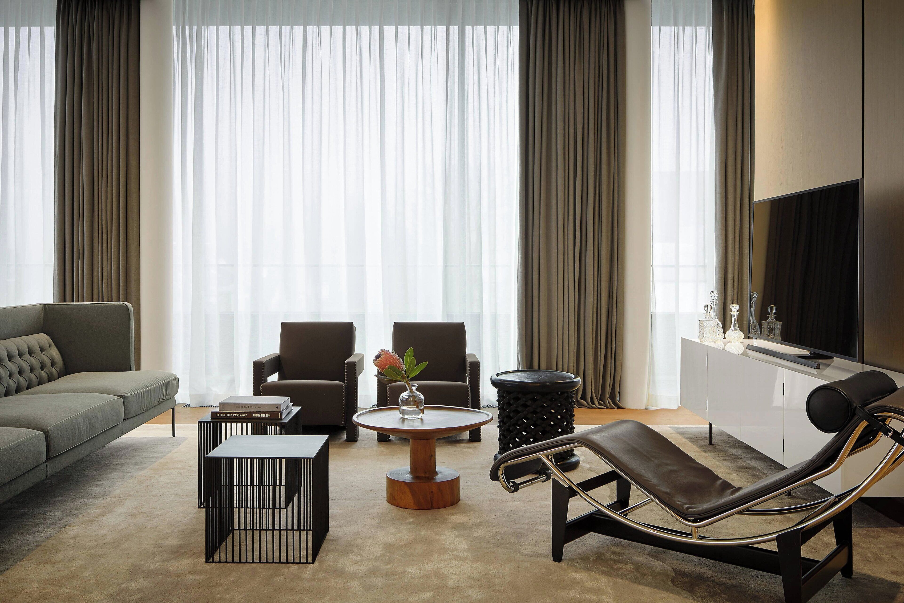 A modern living room with a sofa, two armchairs, a coffee table, a TV, and a reclining chair.