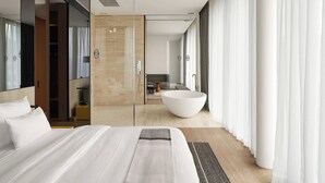 A modern hotel room with a large bed, a walk-in closet, a large bathtub, and a view of the bathroom and living area. - Roomers Baden-Baden, Autograph Collection (Baden-Baden)