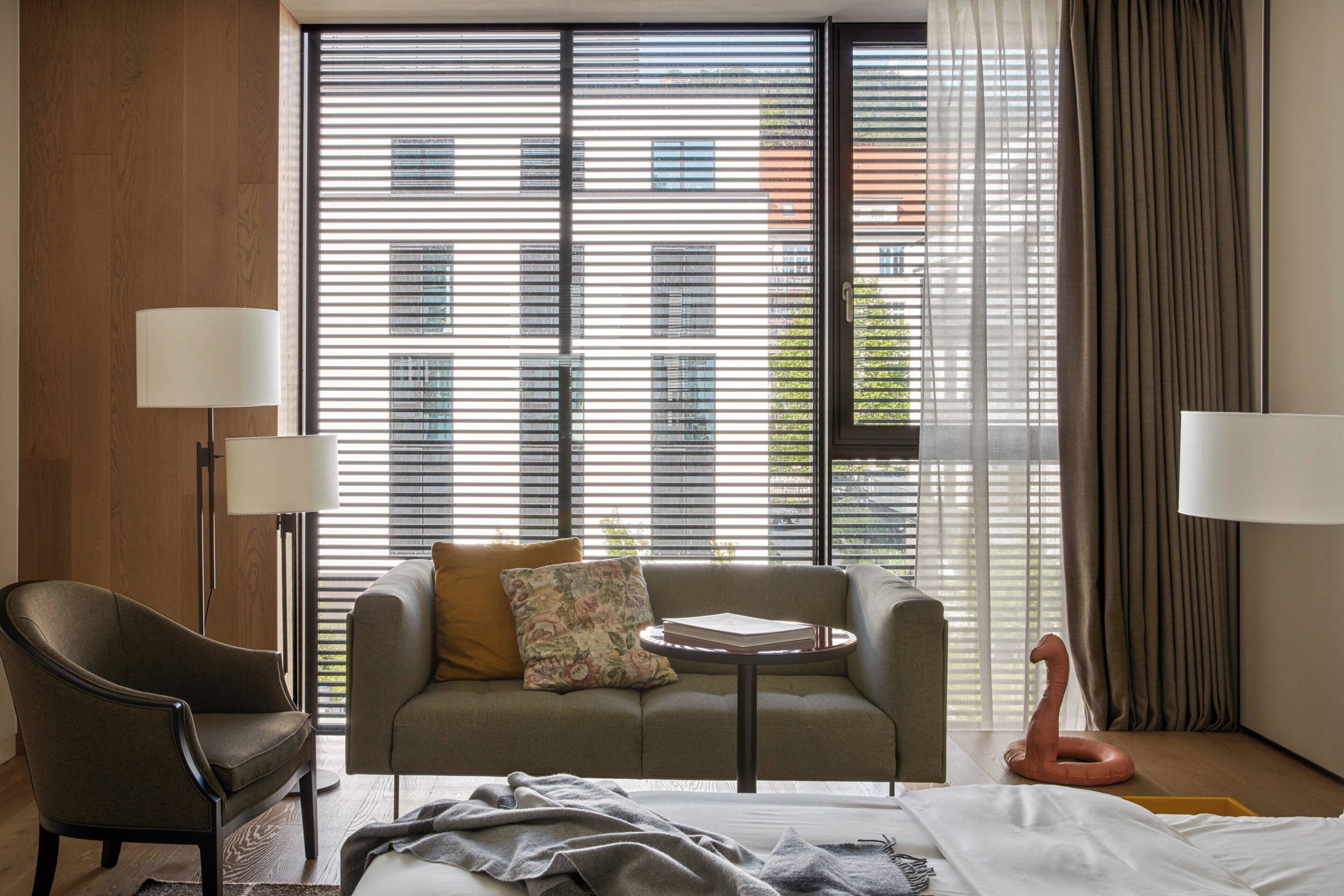 Una habitación de hotel con sofá, una silla, una mesita y una cama.