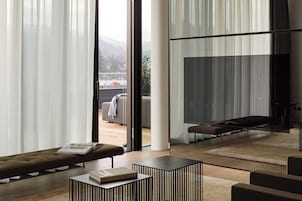 Uma sala de estar moderna com sofá, mesa de centro e divisória de vidro.