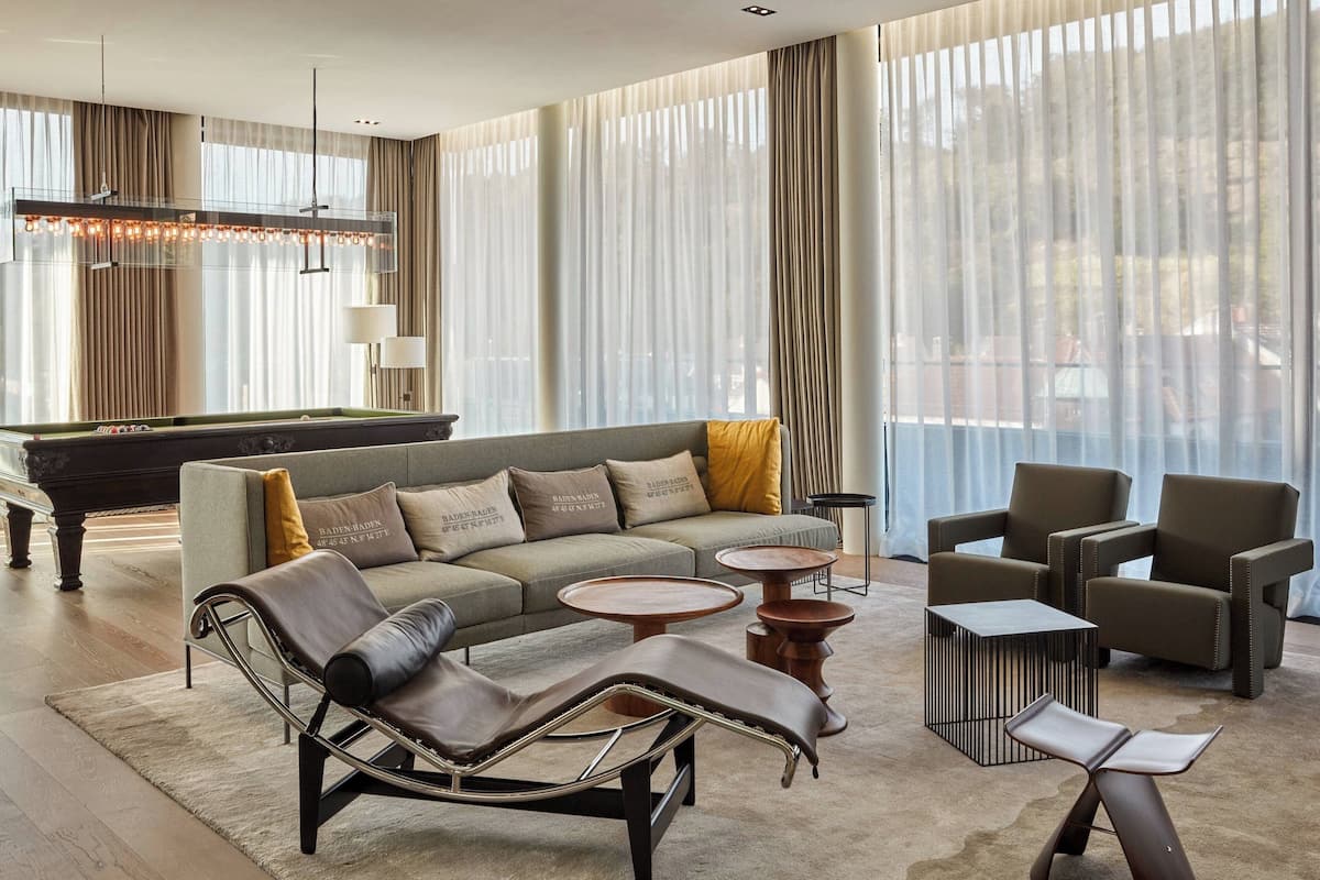 Un salon moderne comprenant un canapé, un fauteuil, une table basse et une table de billard.