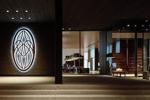 Een modern interieur met een opvallend logo op de muur, een zithoek met tafels en een trap naar een hoger niveau.