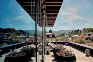 Terraço no telhado com vista para a paisagem urbana, incluindo um edifício em formato de cúpula e uma colina ao longe.