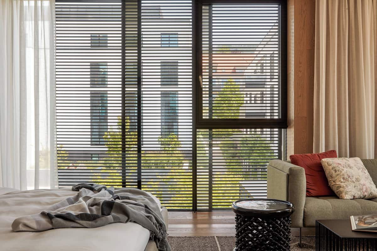 Une chambre d’hôtel moderne dotée d’une grande fenêtre, d’un lit, d’un canapé et d’une table basse.