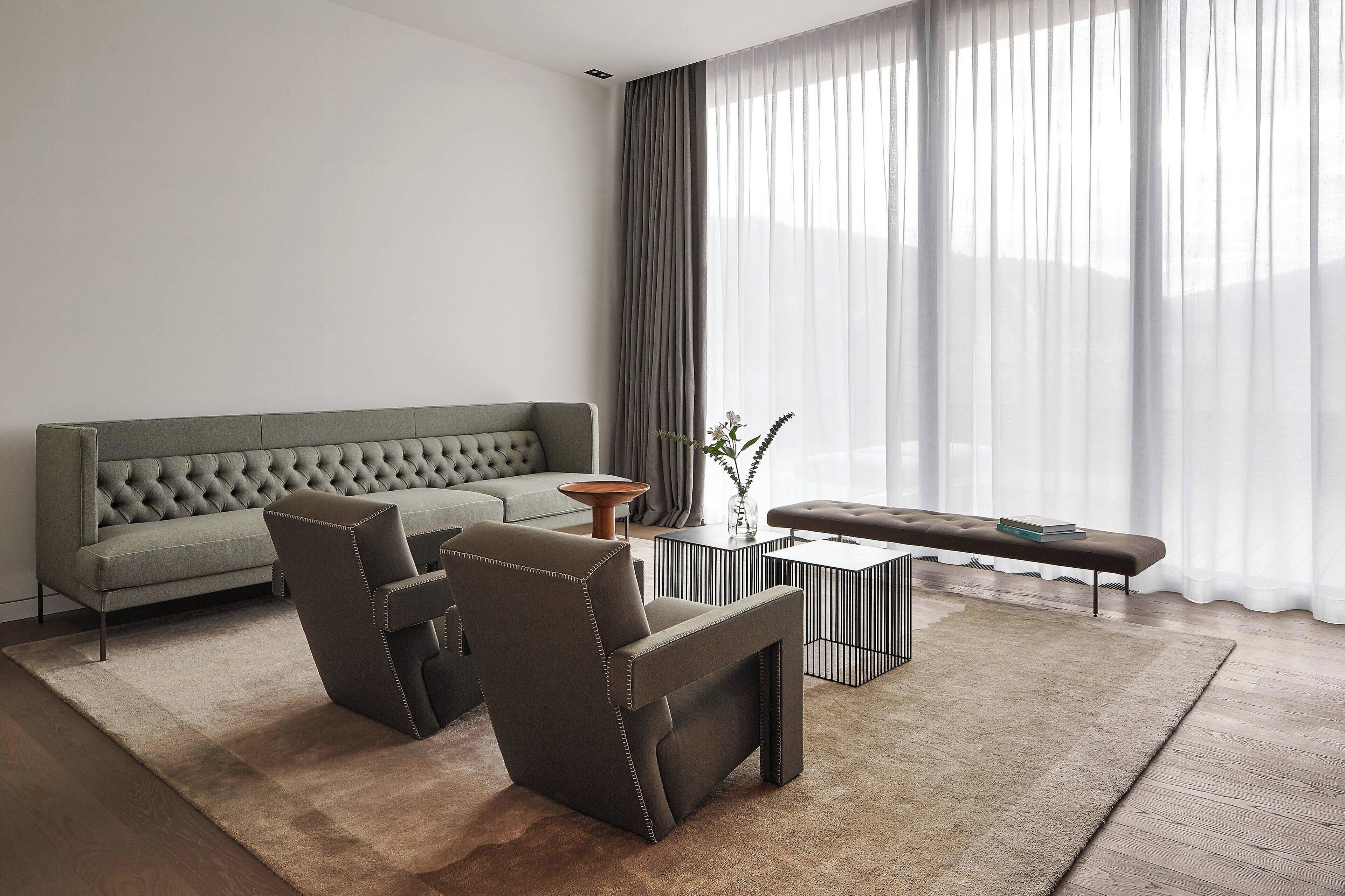 A modern living room with a grey sofa, two armchairs, a coffee table, and a bench.