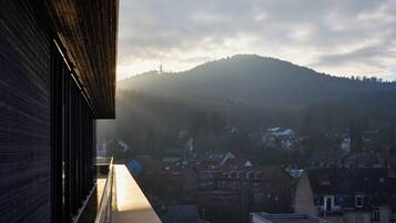 Een gebouw met een lang, smal balkon met uitzicht op een stad en een heuvel.