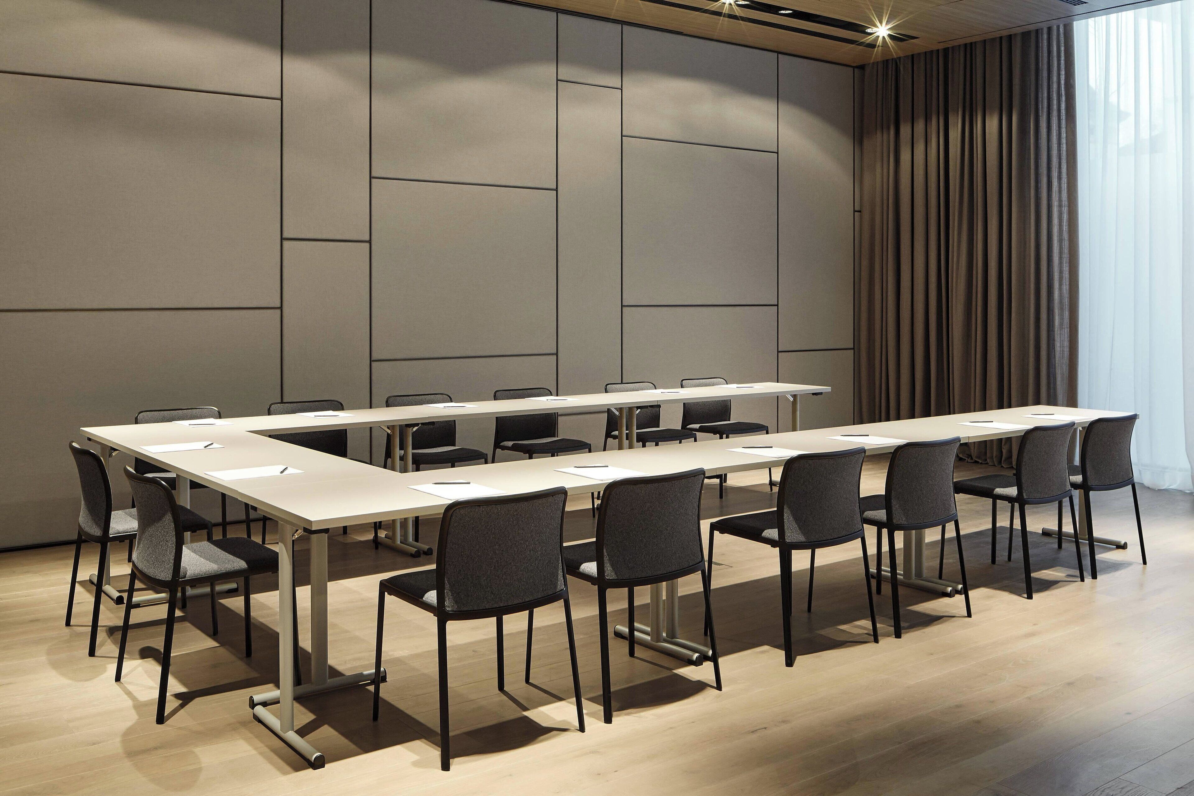 Uma sala de conferências com uma mesa comprida, várias cadeiras e um design moderno.