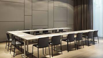 Uma sala de conferências com uma mesa comprida, várias cadeiras e um design moderno.