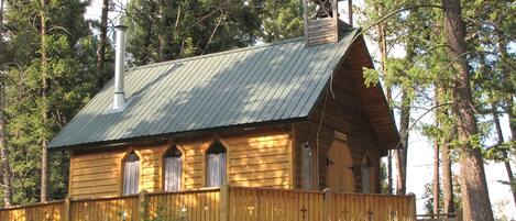 Una cabaña de madera con techo metálico, un campanario y un balcón.