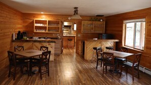Una baita in legno con cucina, sala da pranzo e bancone.