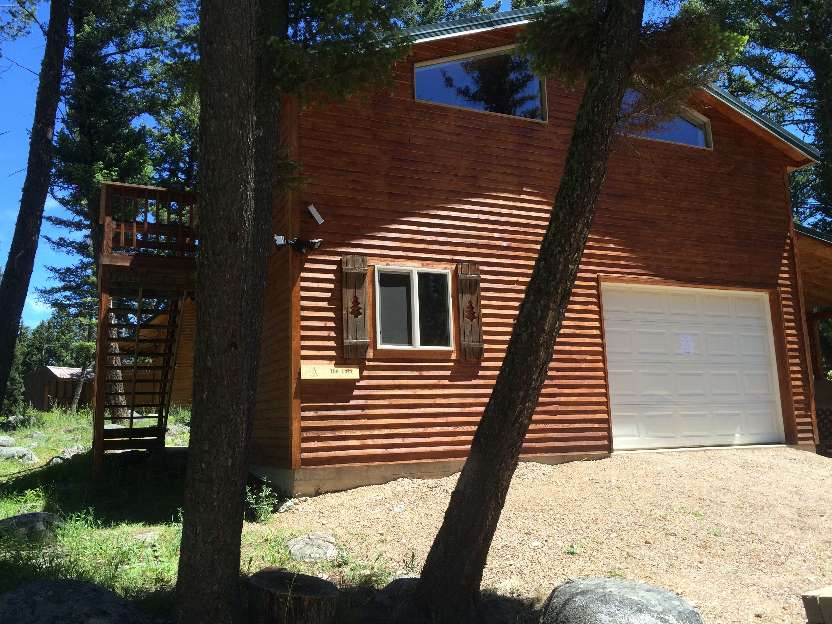 A two-story log cabin with a garage and a small deck.