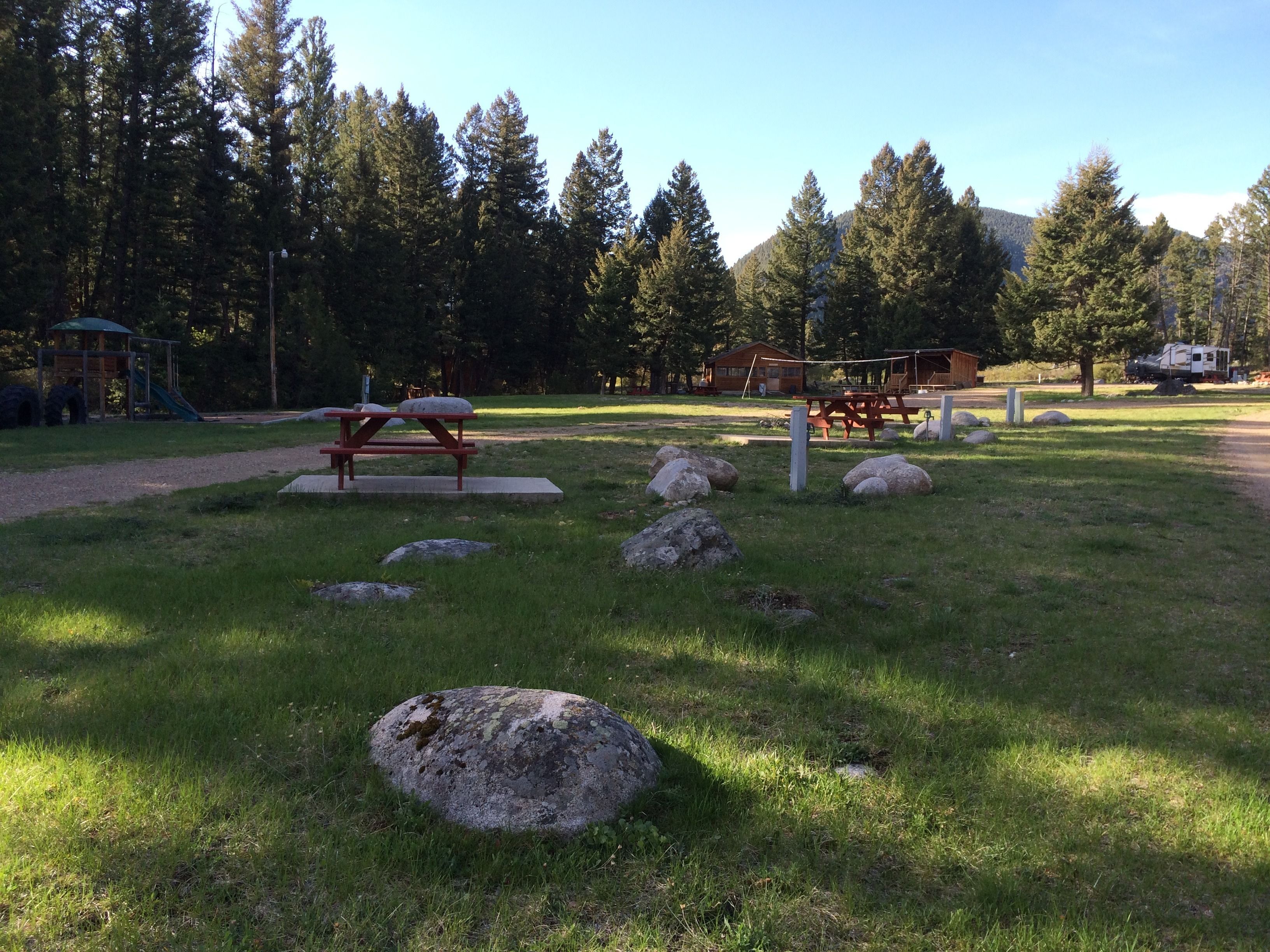 A picnic area with a wooden table and benches, surrounded by rocks and grass.