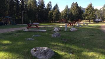 A picnic area with a wooden table and benches, surrounded by rocks and grass.