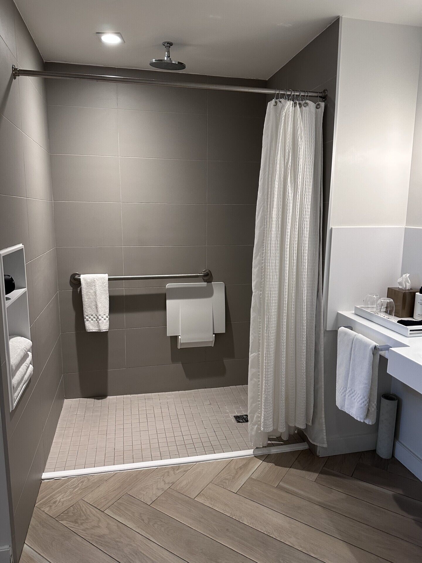 Un baño moderno con ducha, toallero, inodoro y lavabo.