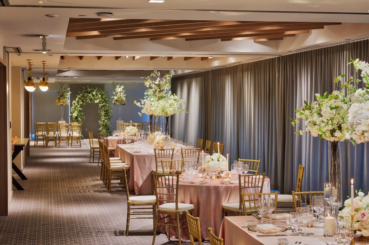 A banquet hall with long tables, gold chairs, and floral centerpieces.