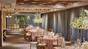 A banquet hall with long tables, gold chairs, and floral centerpieces.