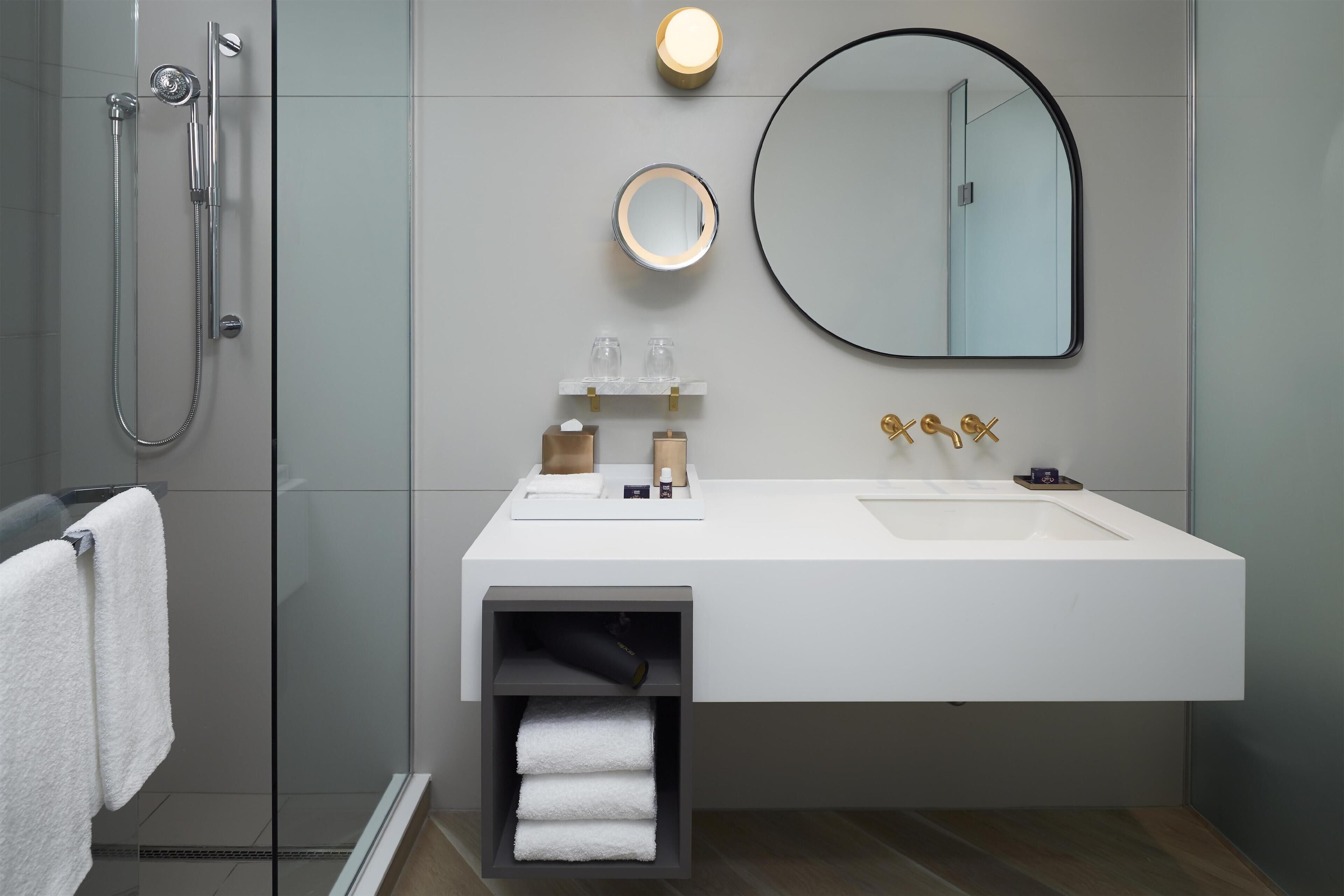 A modern bathroom with a built-in shower, a large mirror, and a vanity with a sink.