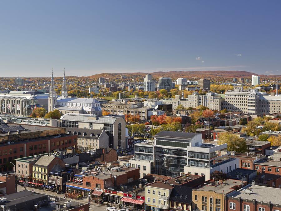 A cityscape with a mix of historic and modern buildings, including a prominent church with twin spires.