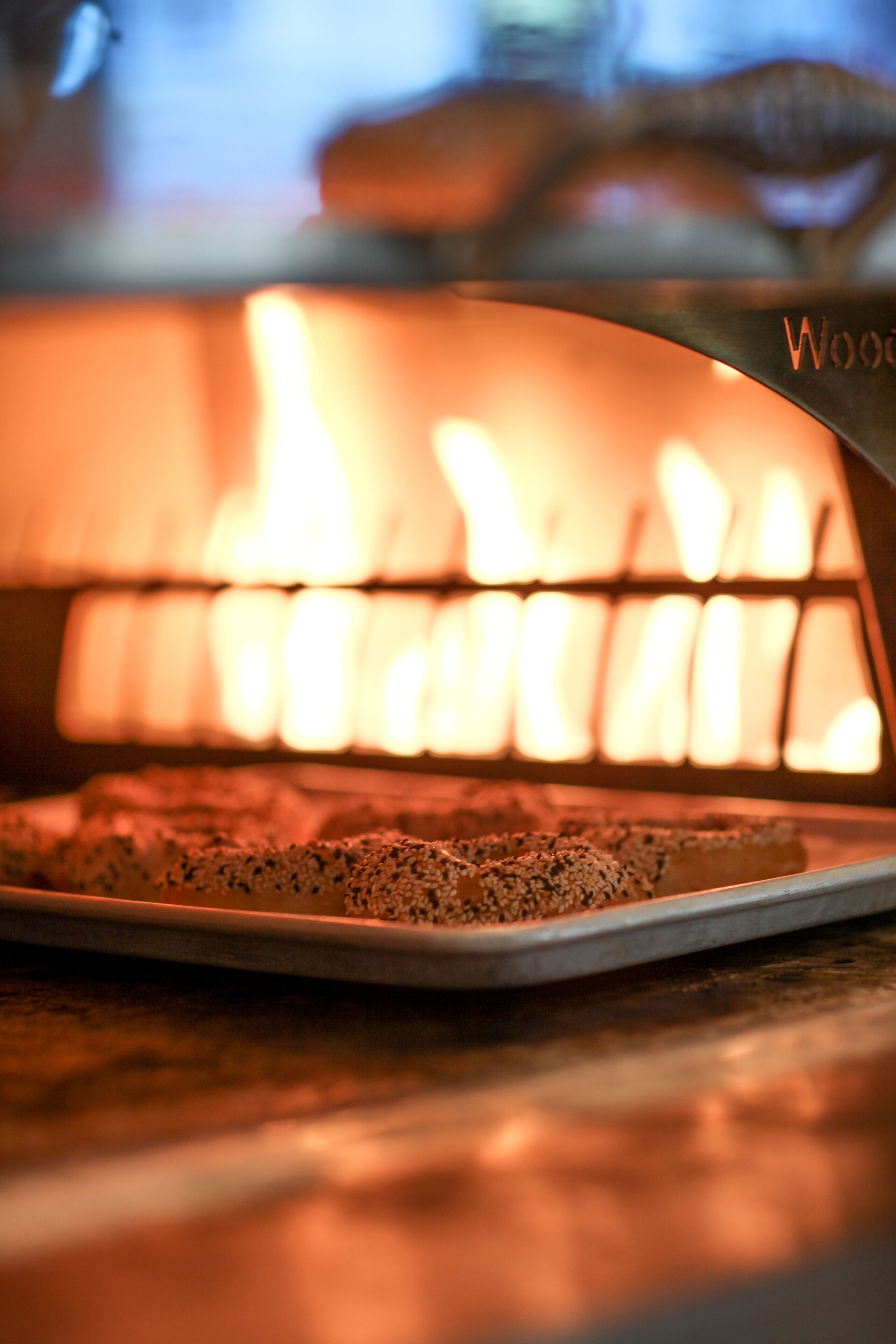 Un four à pizza avec un feu incandescent, une pizza sur une plaque et une table en bois.