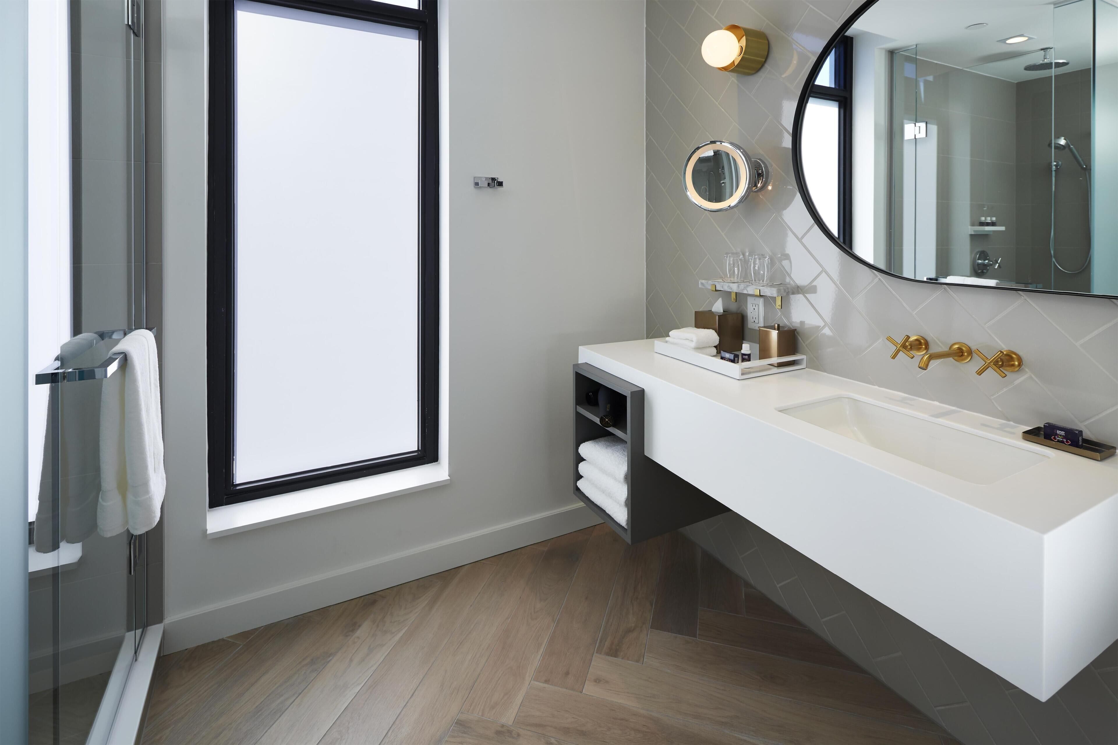 Un baño moderno con un amplio ventanal, un lavabo blanco y un espejo.
