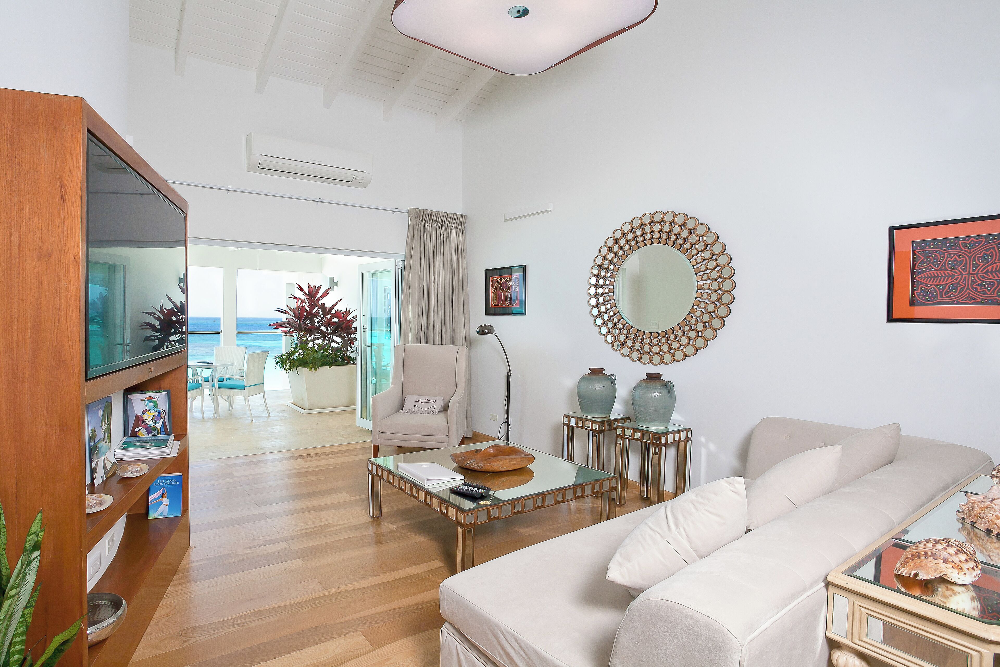 A spacious living room with a sofa, coffee table, and a view of the ocean through large windows.