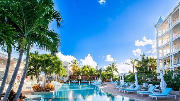 Un área de piscina en un resort, con sillones de descanso y palmeras.
