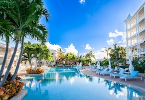 A resort pool area with lounge chairs and palm trees.