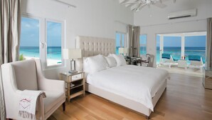 Un dormitorio espacioso con una cama grande, una zona de estar con vistas a la playa y un ventilador de techo.