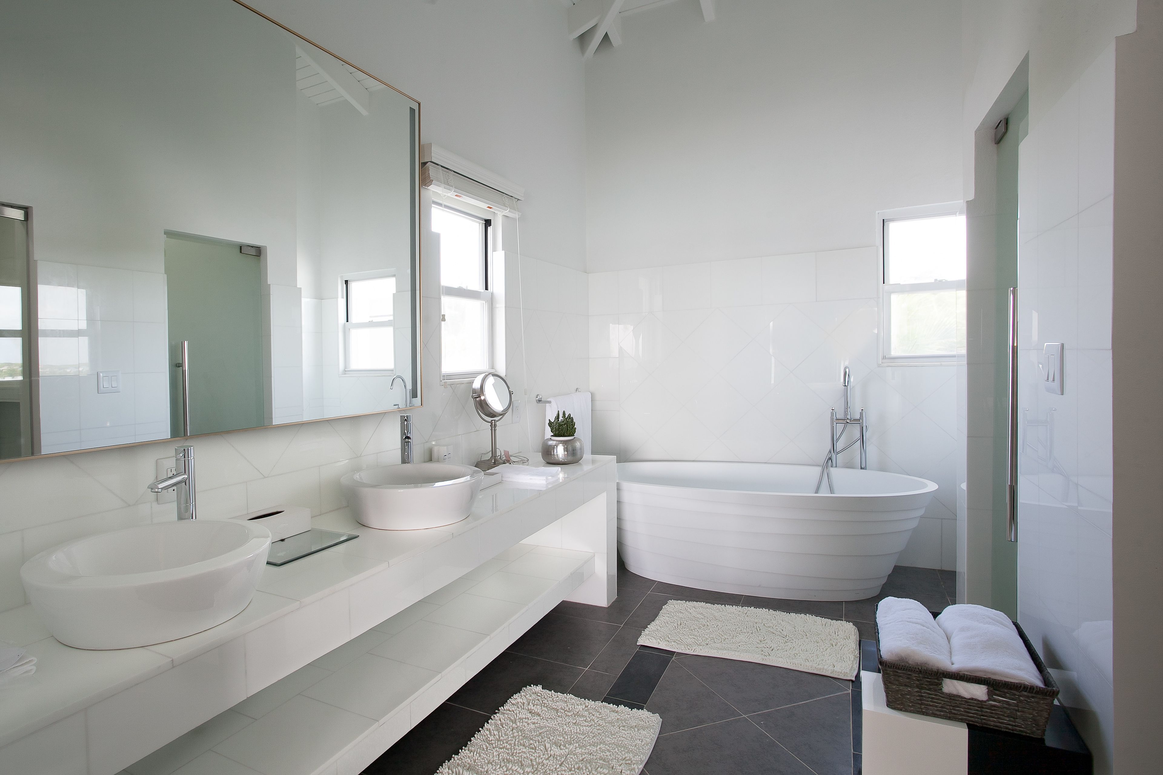Une salle de bain moderne avec une grande baignoire, un meuble-lavabo à deux vasques et un grand miroir.