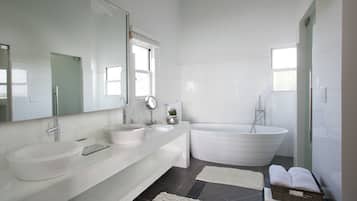 A modern bathroom with a large bathtub, a double sink vanity, and a large mirror.