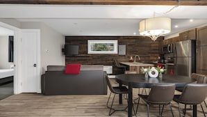 Una cocina moderna con una isla central, paneles de madera en la pared y un comedor con una mesa redonda y sillas.