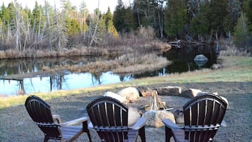 Ein Sitzbereich am Seeufer mit Adirondack-Stühlen und einem Feuerkorb.