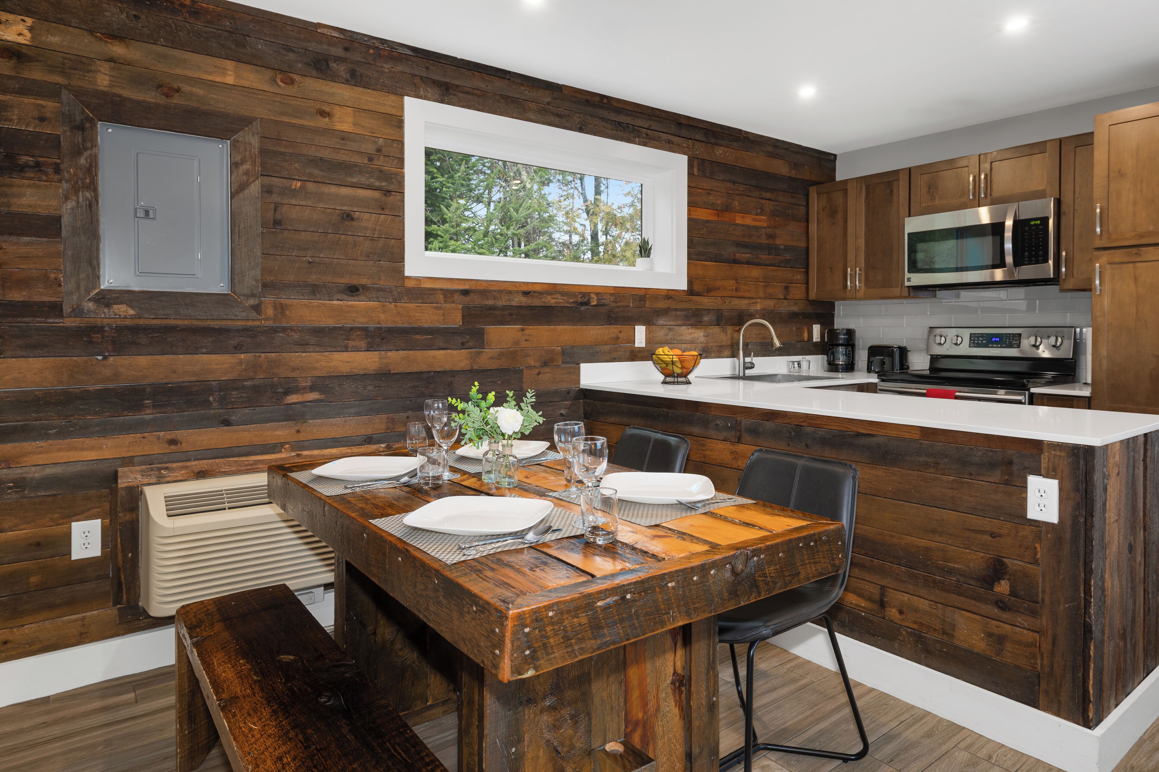 A modern kitchen with wooden paneling, a dining table set for four, and built-in appliances.