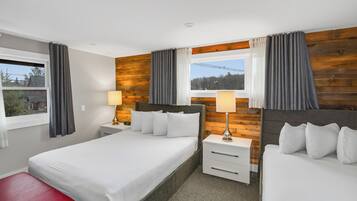 Ein Hotelzimmer mit zwei Betten, einer roten Bank, Holzwandverkleidung und einem Fenster mit Vorhängen.