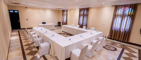 A conference room with a long table, white chairs, and a patterned floor.