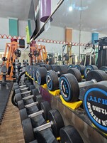 Un gimnasio con filas de mancuernas y máquinas de pesas.
