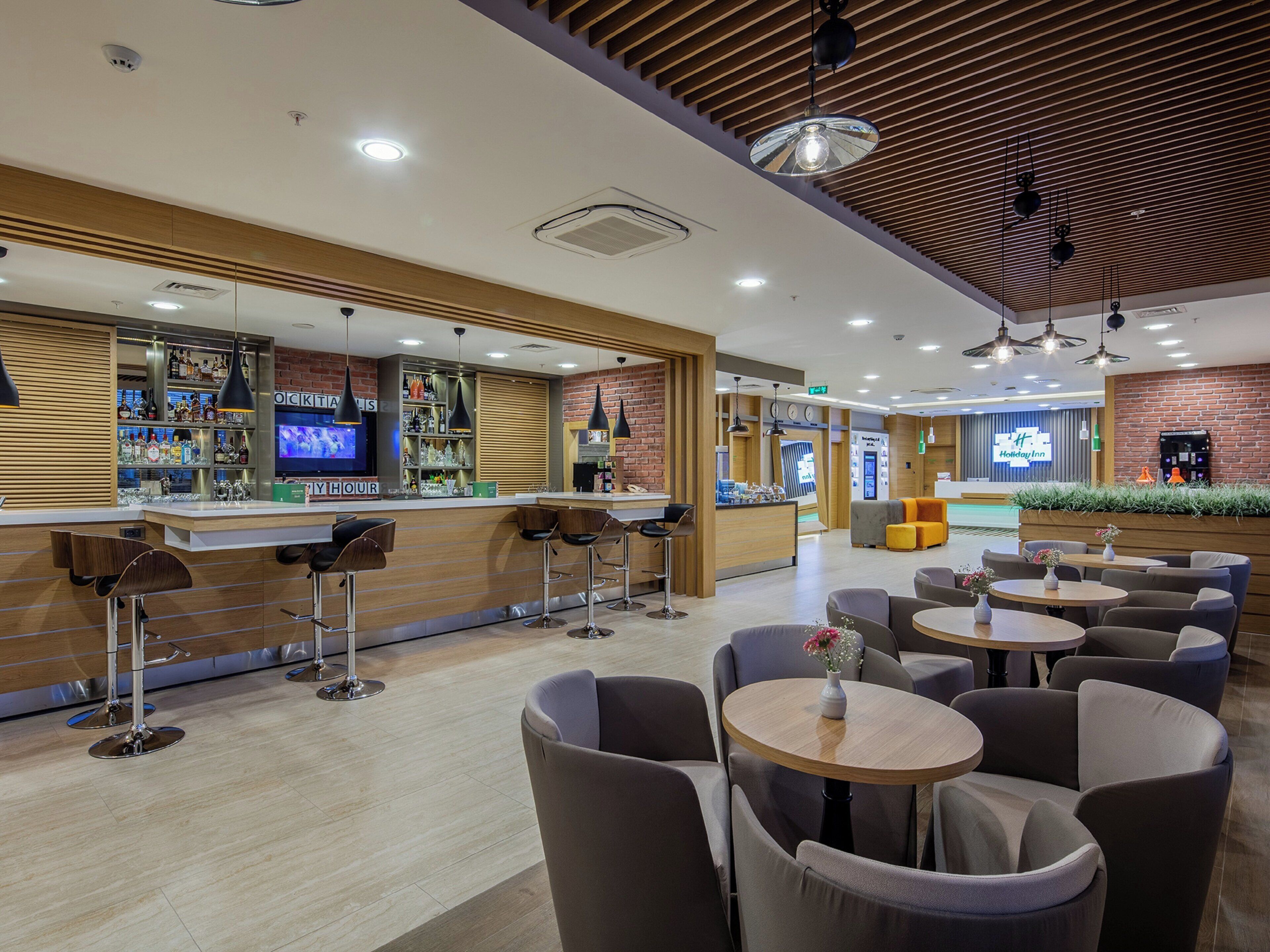 A hotel lobby with a bar area, seating arrangements, and a reception desk.