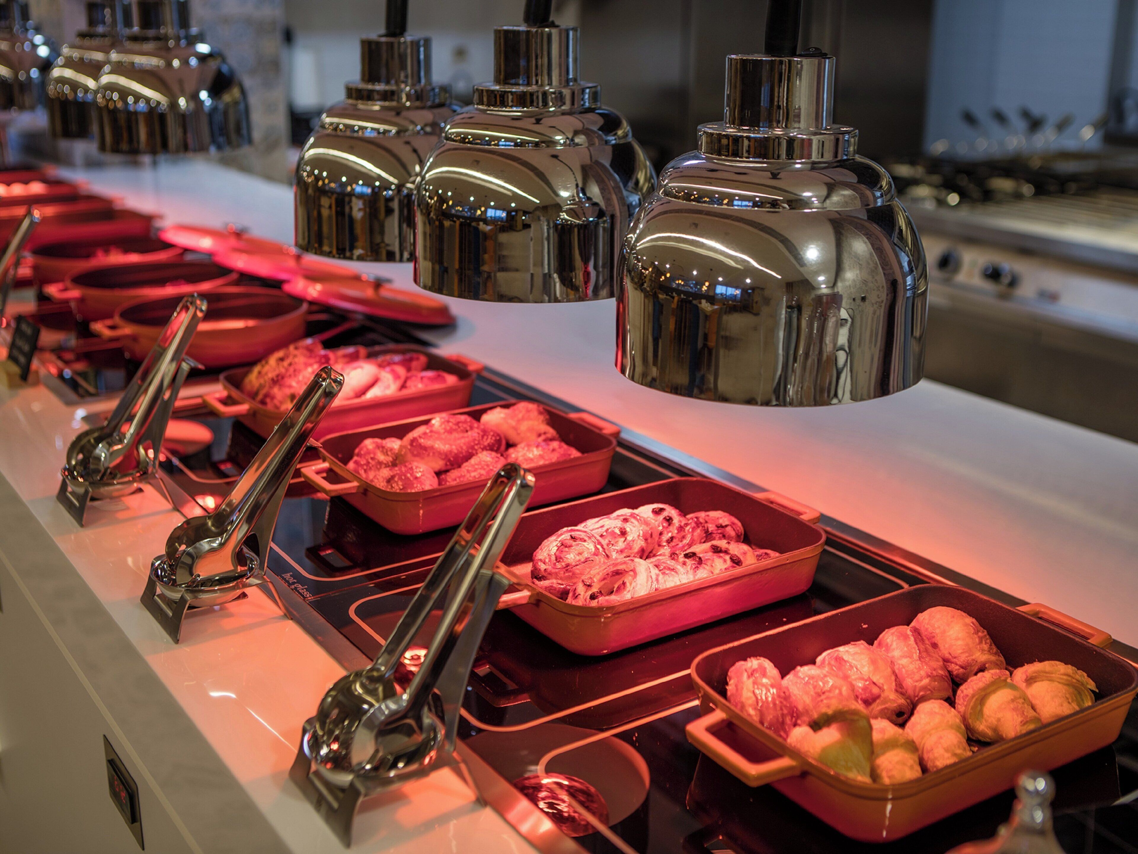 A buffet setup with various food items and serving utensils.