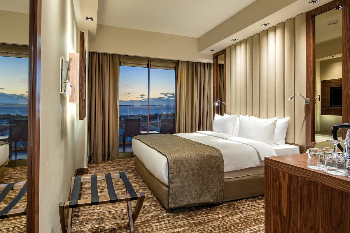 A hotel room with a large bed, a wooden desk, and a view of the mountains.