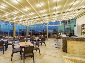 A spacious indoor area with tables and chairs, large windows, and a ceiling with lights. - Holiday Inn Antalya - Lara by IHG (Antalya)