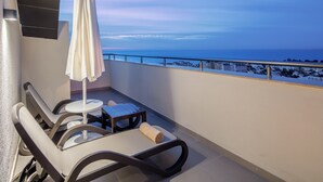 A balcony with a table, chairs, and an umbrella overlooking a coastal view.