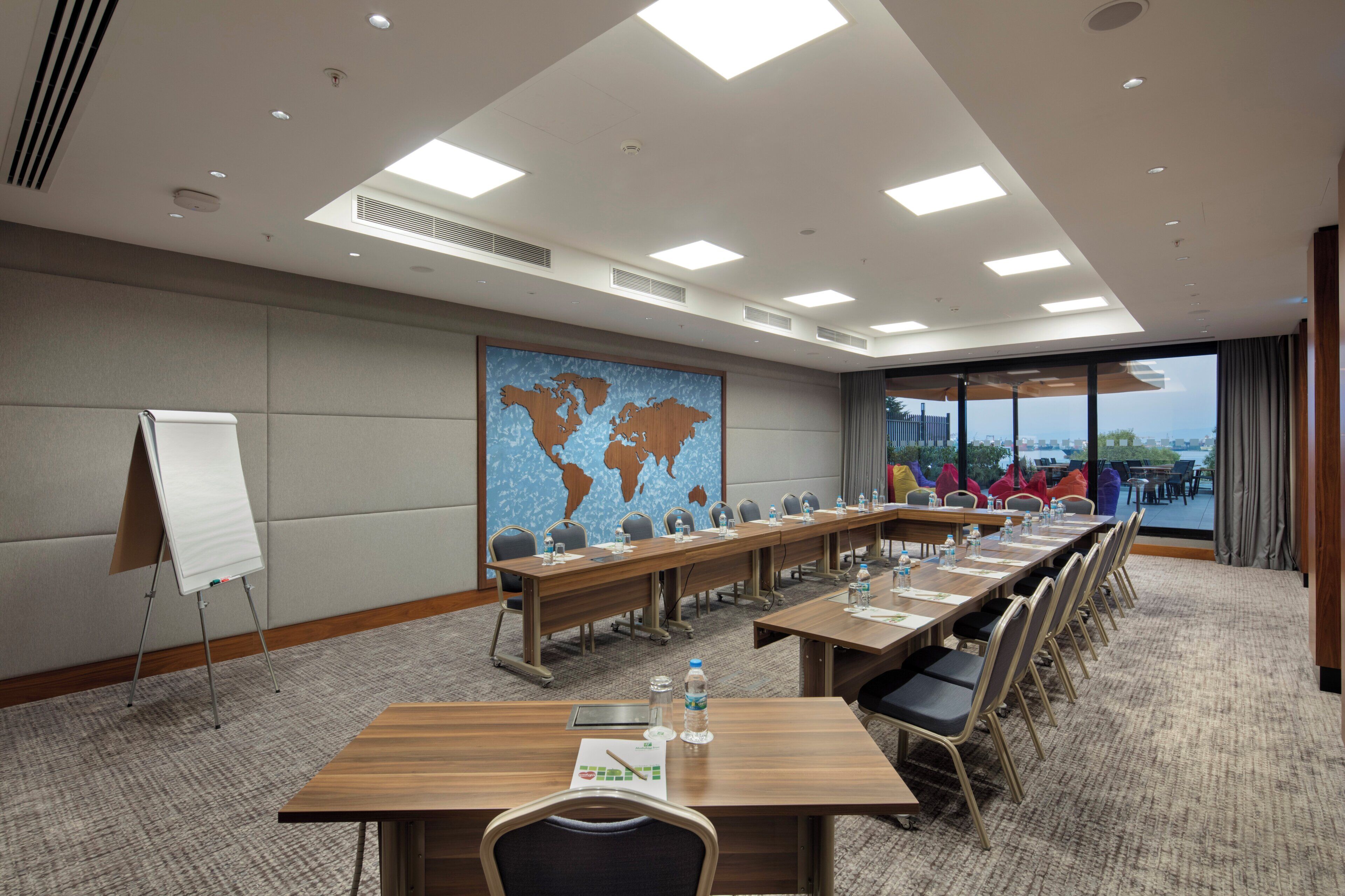 Ein Konferenzraum mit einem langen Tisch, Stühlen, einer Whiteboard-Tafel und einer Weltkarte an der Wand.