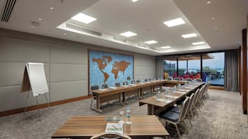 Ein Konferenzraum mit einem langen Tisch, Stühlen, einer Whiteboard-Tafel und einer Weltkarte an der Wand.