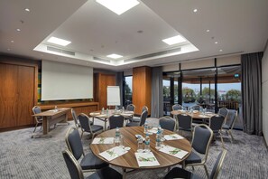 A conference room with a large table, chairs, a projector screen, and a view of the outdoors. - Holiday Inn Istanbul - Tuzla Bay by IHG (Istanbul)