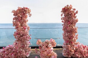 En terrass med en blomsterprydd båge och utsikt över havet.