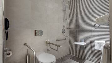 Un baño moderno con inodoro, barras de apoyo, ducha y perchero para toallas.