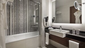 Un baño moderno con ducha de vidrio, tocador con lavabo y un espejo grande.